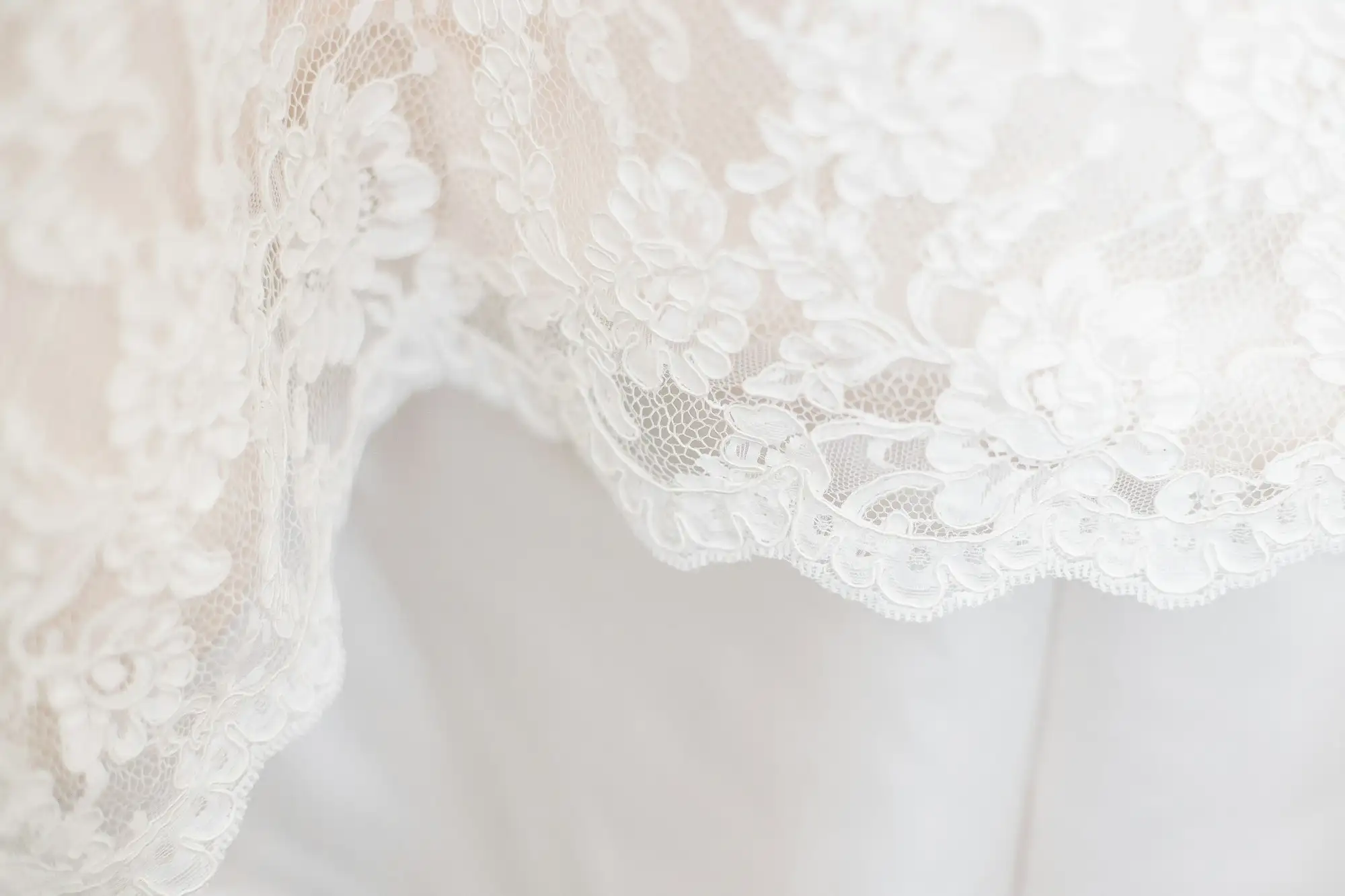 Nærbillede af hvid blonde med blomstermønster over et lyst stof